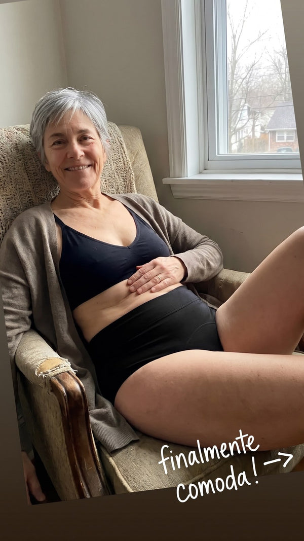 Donna seduta in poltrona vicino alla finestra, con lo slip lavabile Fresia nero a vita alta