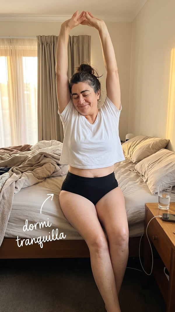 Donna che si stiracchia al risveglio, seduta sul letto, con lo slip lavabile Fresia nero a vita alta